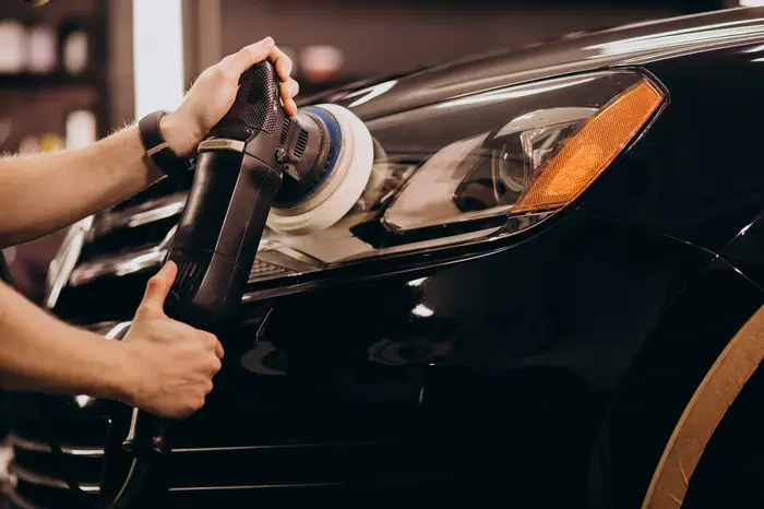Car detailing technician polishing a white car